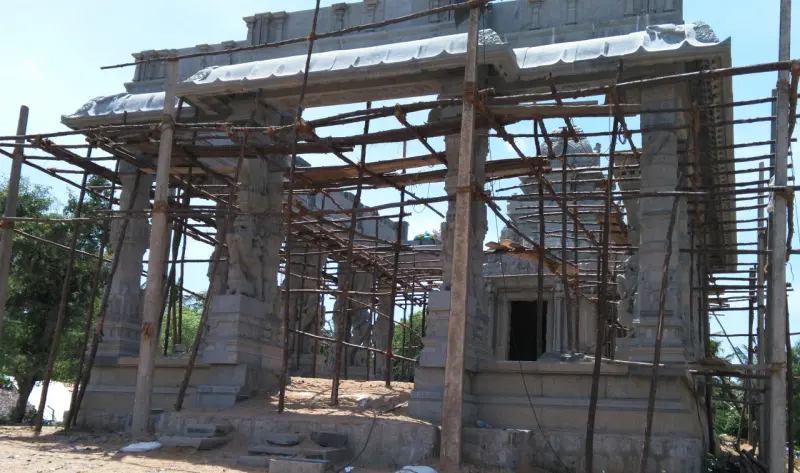 A new stone hall with carved pillars stands inside a frame of bamboo scaffolding.