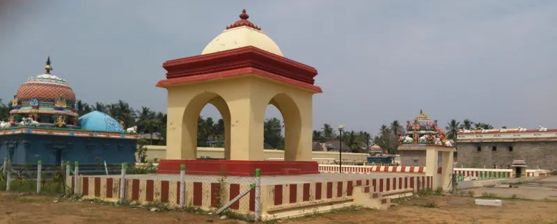 A yellow pavilion with arches and a red base, a red-and-white striped wall in front