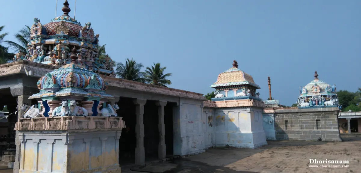 Courtyard with colourful shrine towers, a flagstaff and a pillared hall under a clear sky