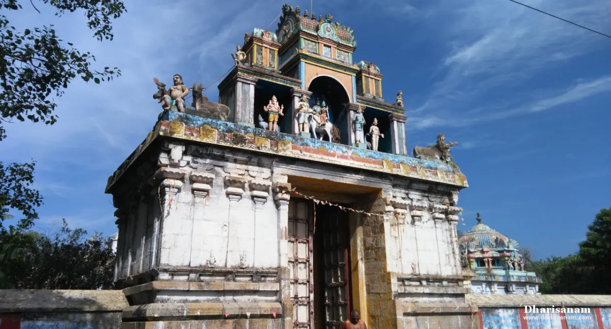 White stone gateway with a doorway and a small painted tower above, against a blue sky
