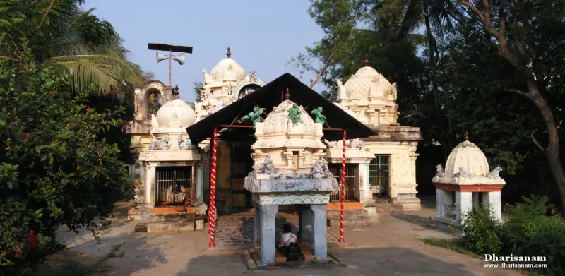 White shrines with tower tops, a shelter on striped poles, trees, and a loudspeaker post
