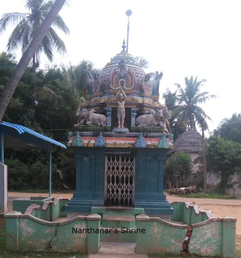 A small blue-green shrine with a domed roof and a metal grille door