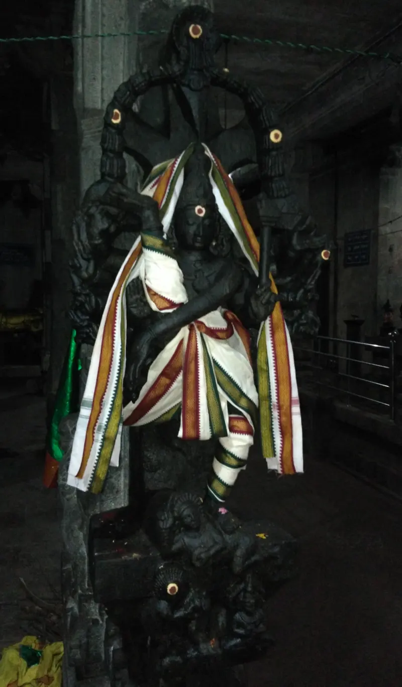 A tall dark stone figure carved on a pillar