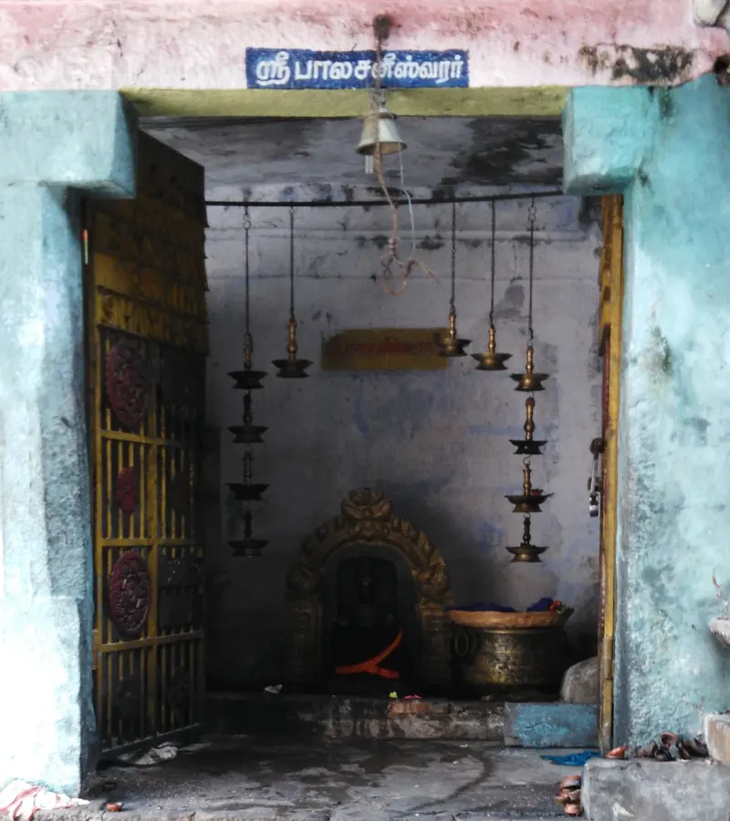 A small shrine with hanging brass lamps and a Tamil name board above the doorway.