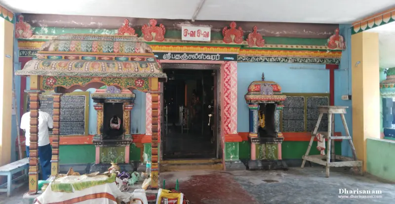 A shrine doorway with a Tamil name board above it, flanked by two small shrines and black boards on the wall