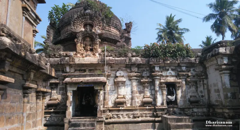 Carved stone walls and a domed tower with a seated figure in its upper niche, palms beyond
