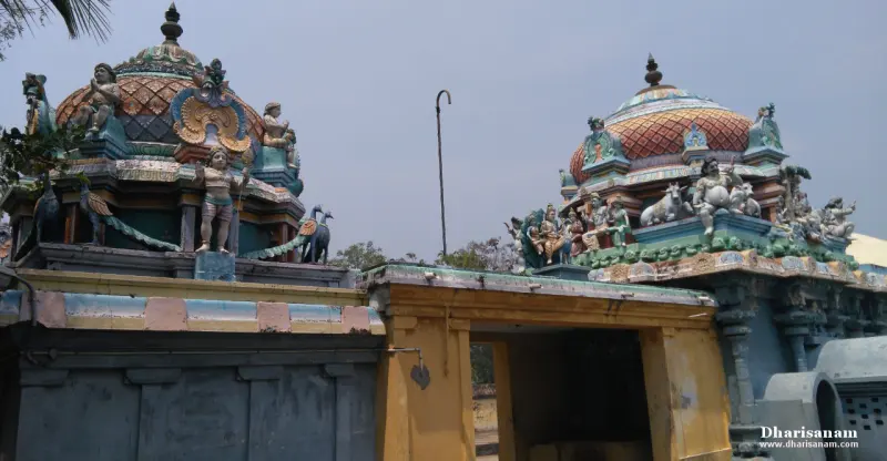Two domed shrine towers with painted figures, rising above low rooftops under a hazy sky