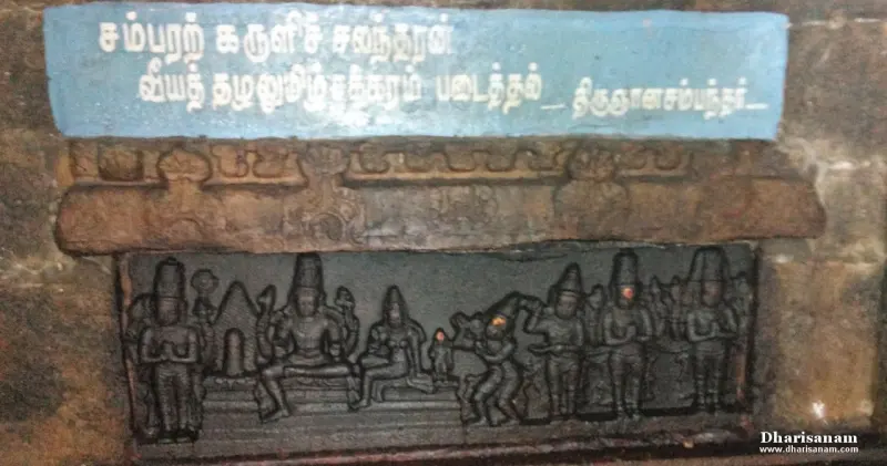 A carved relief of several figures and a lingam, under a blue board with a Tamil verse