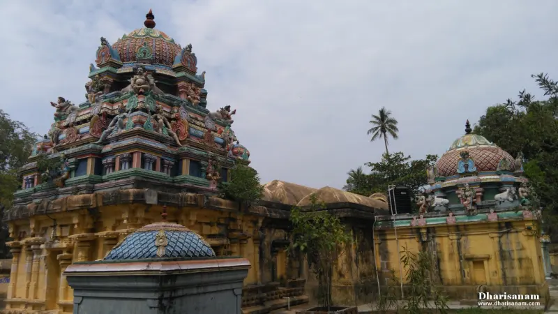 Tower in green, pink and blue with sculpted figures, and domed roofs in front of a cloudy sky