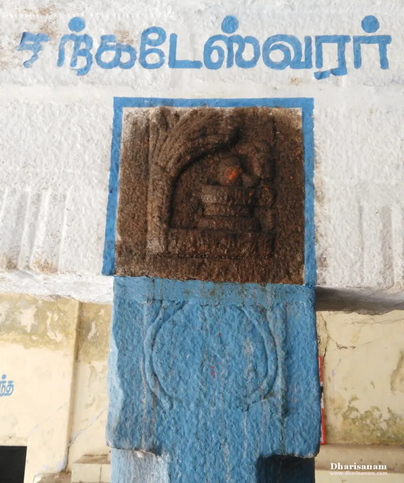 Brown stone relief set in a blue-framed square on a white pillar, with a Tamil name written above