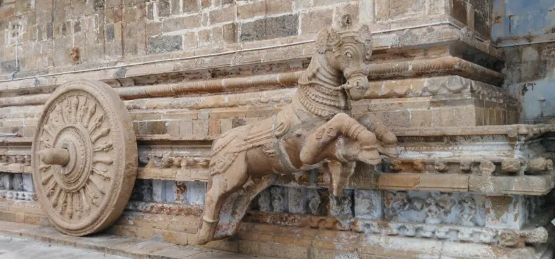Carved rearing horse beside a detailed stone chariot wheel