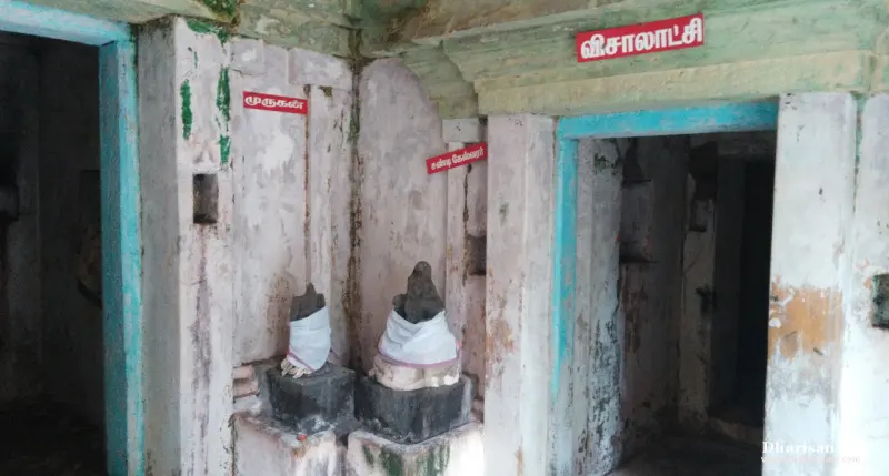Two small idols in white cloths on stone bases, with red boards for Murugan and Chandikeswarar; a Visalakshi doorway.