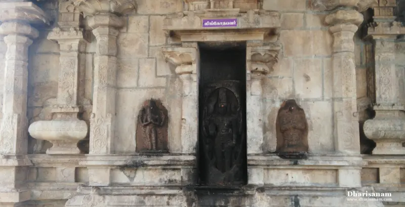 Carved stone wall with a tall dark niche holding a standing idol, and smaller idols on both sides