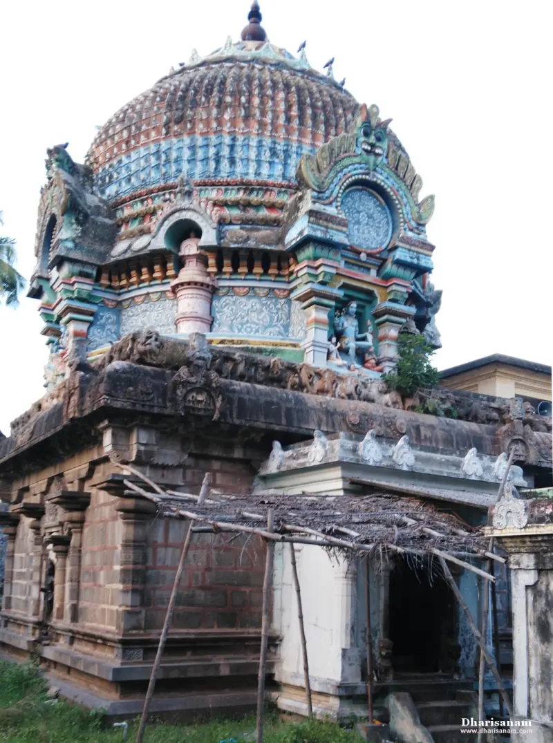 Large domed sanctum tower with painted figures above an old brick and stone wall and a small porch