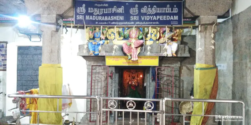 A shrine entrance with a name board and painted figures above, the goddess visible inside