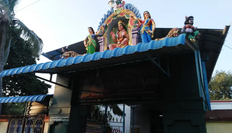 A gateway under a blue roof with painted deity figures on top and a dark signboard below.