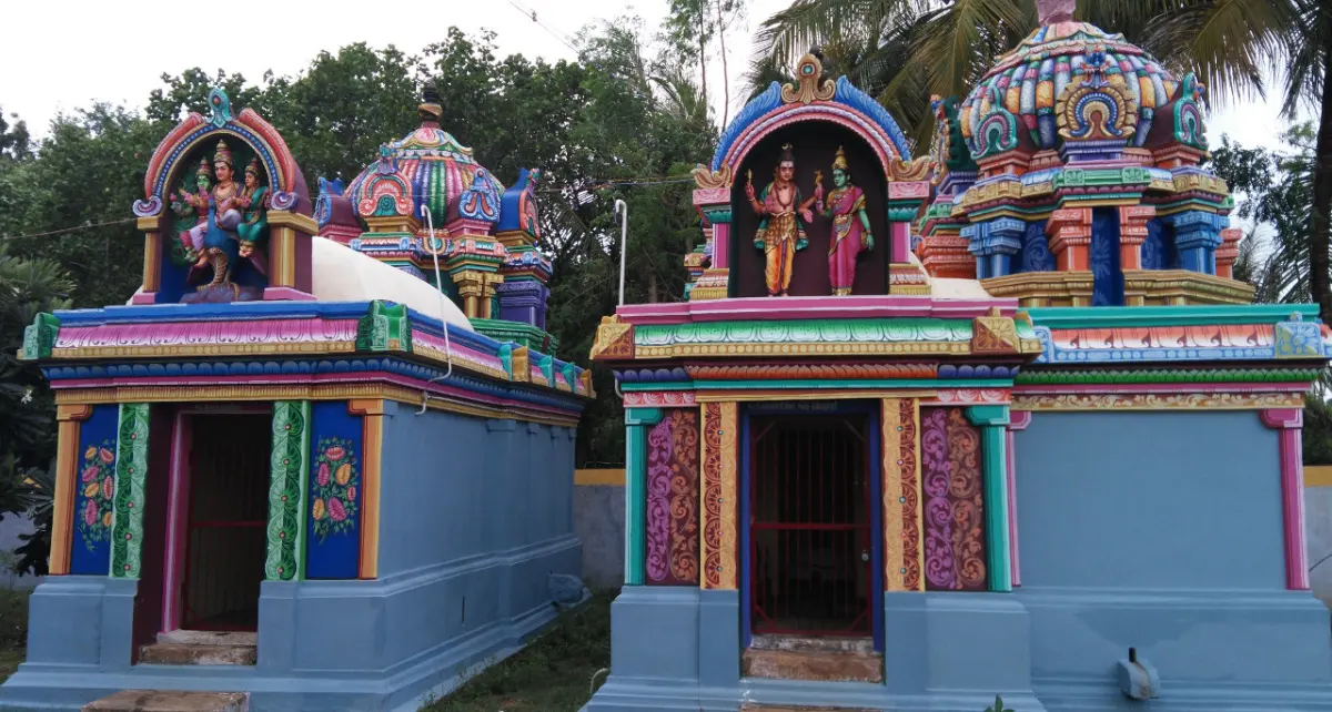 Two small shrines with painted towers and figures, among trees