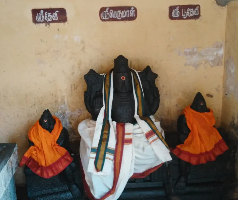 A black stone Perumal in the centre with a smaller idol on each side, under Tamil labels for Sreedevi and Poodevi.