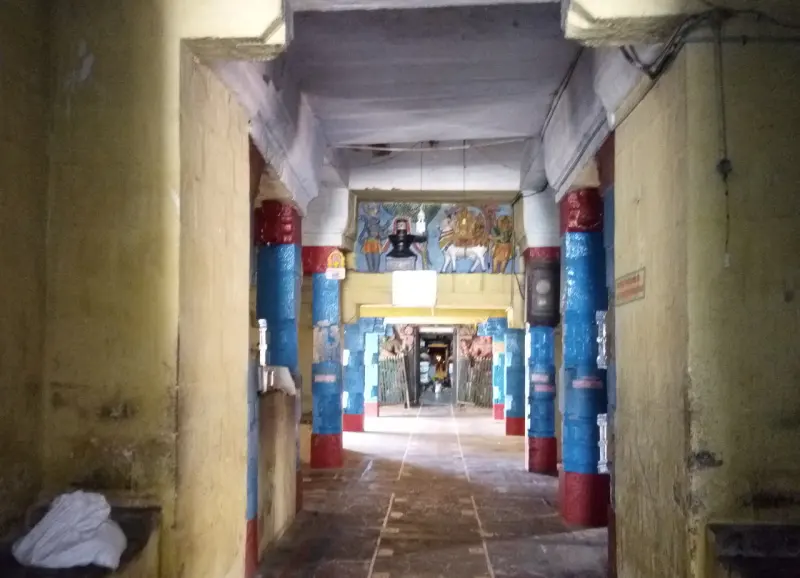 Long corridor with blue and red pillars and a painted panel above the far doorway