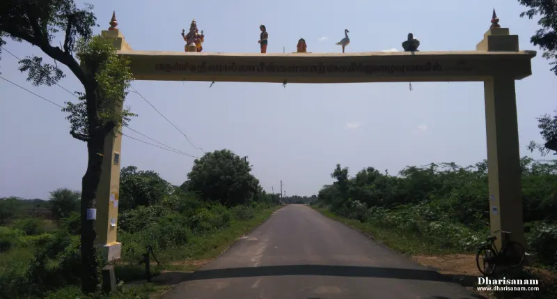 A yellow arch with small idols over a tree-lined road