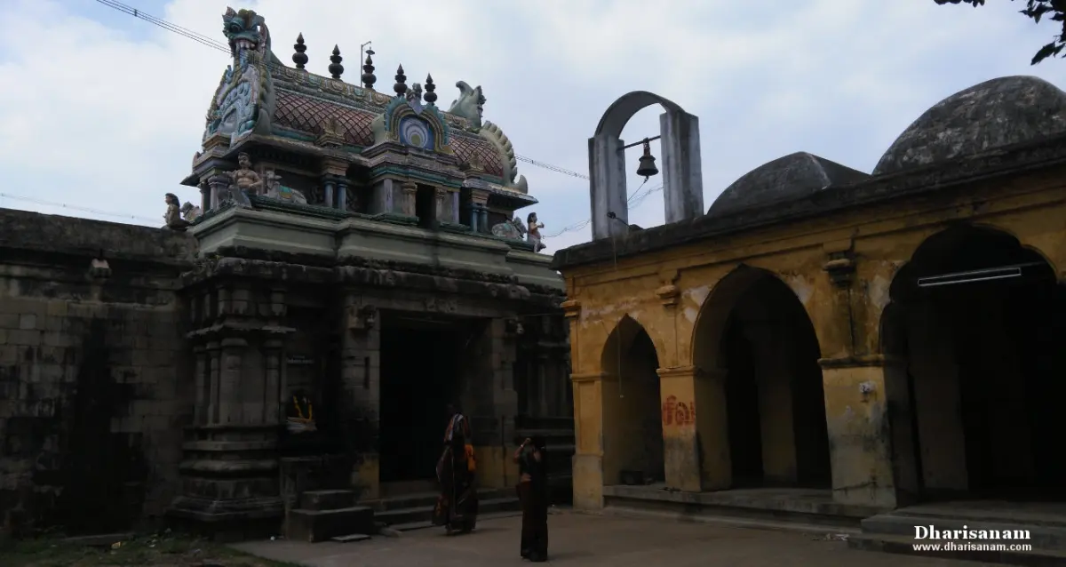 A painted tower over a stone doorway, with two visitors, and a yellow arcaded hall with domes on the right