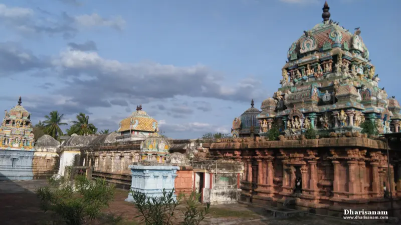 Painted towers rise above the red stone walls of the temple under a cloudy sky.