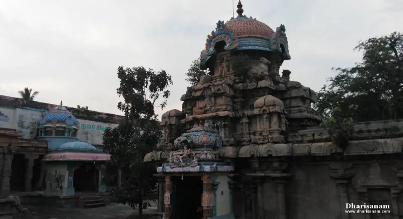 A weathered stone tower topped with a painted dome, with a small porch below and trees around.