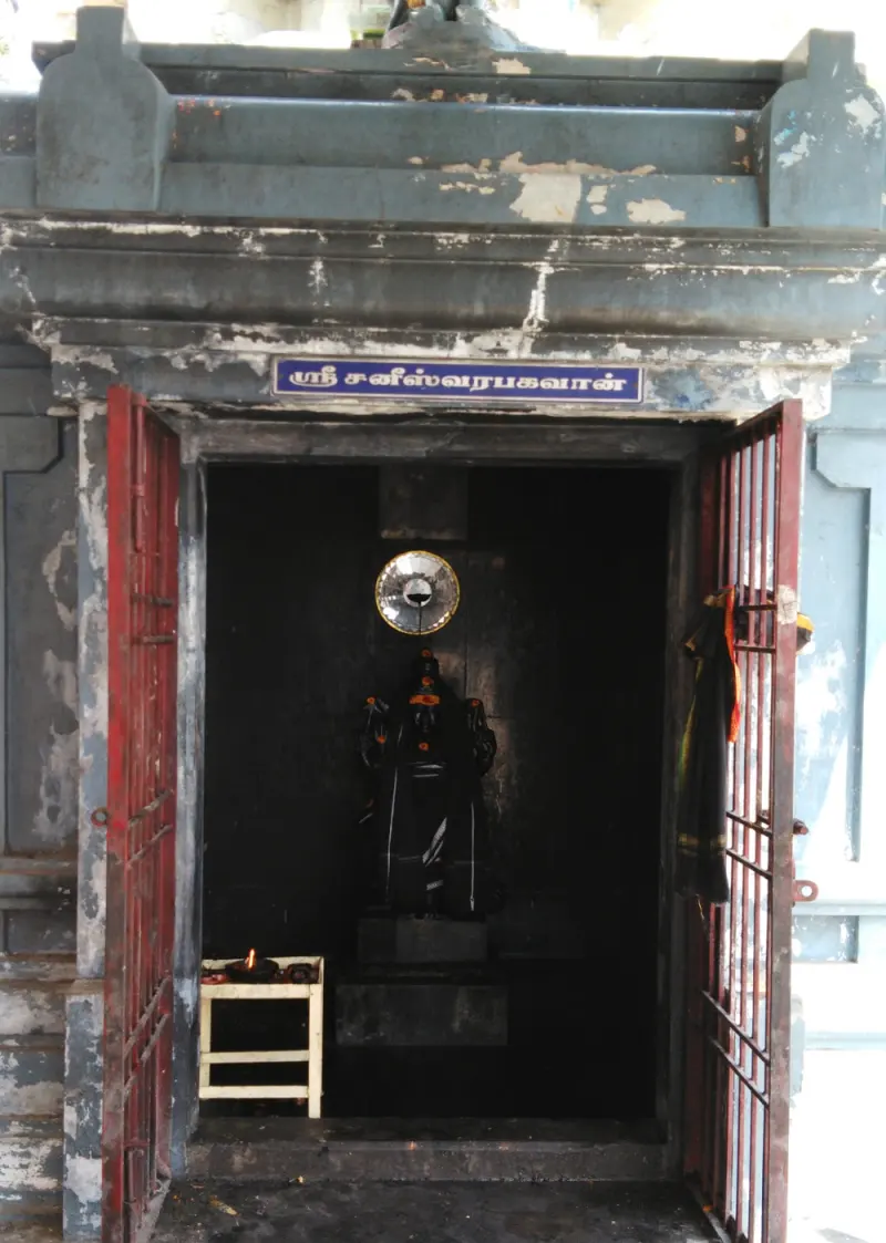 Dark shrine with iron-barred doors, a black idol and a small oil lamp