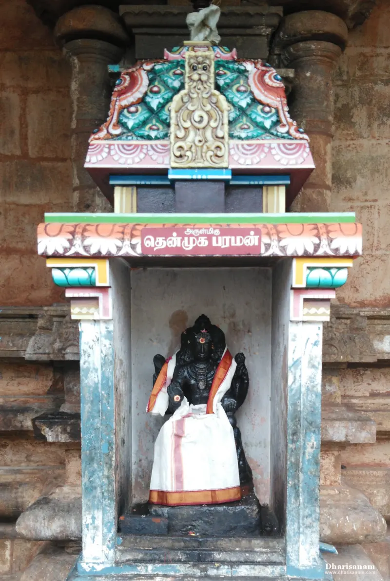 Dark stone idol in a niche on the wall, dressed in white and orange cloth