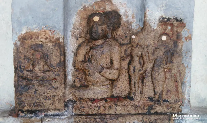 A worn stone relief with a seated figure at the centre and two standing figures at the right