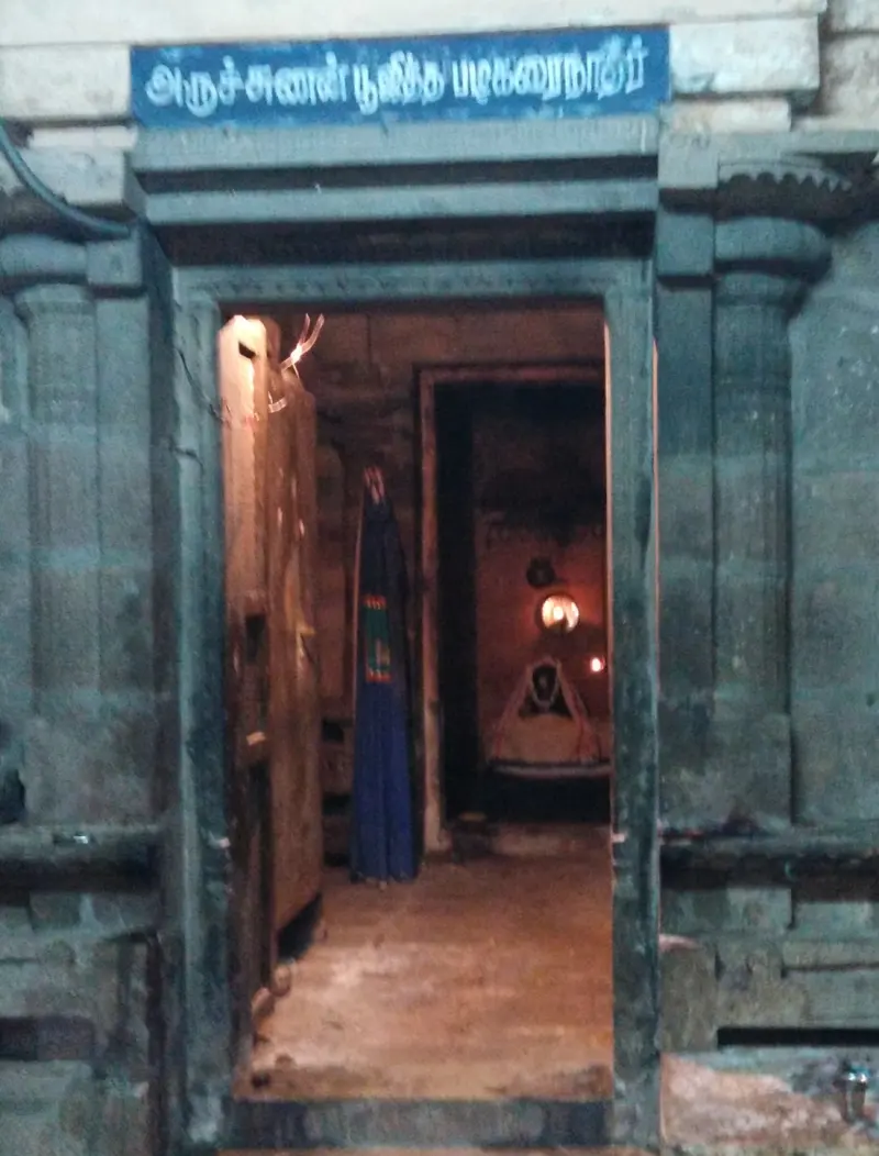A doorway with a Tamil board leading to a lamp-lit shrine