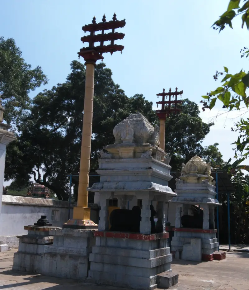 Two white Nandi pavilions with tall flag posts under a clear sky