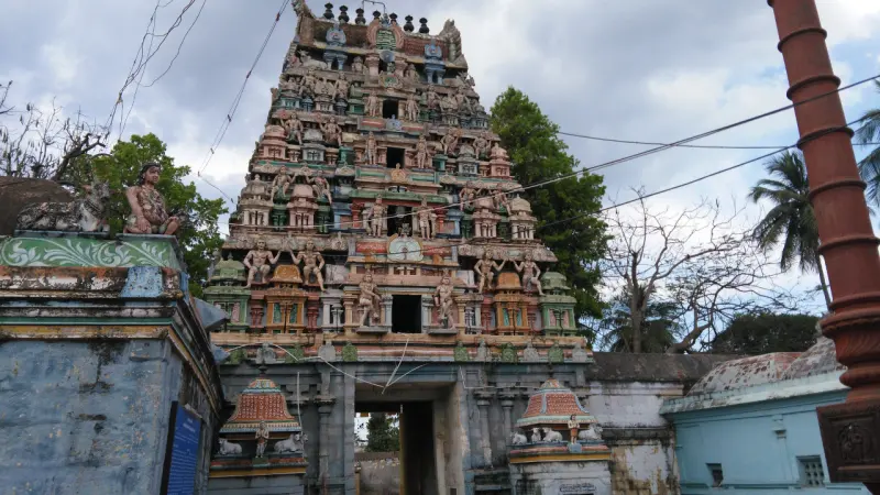 Tall tiered gopuram covered with figures, with a red flagstaff on the right