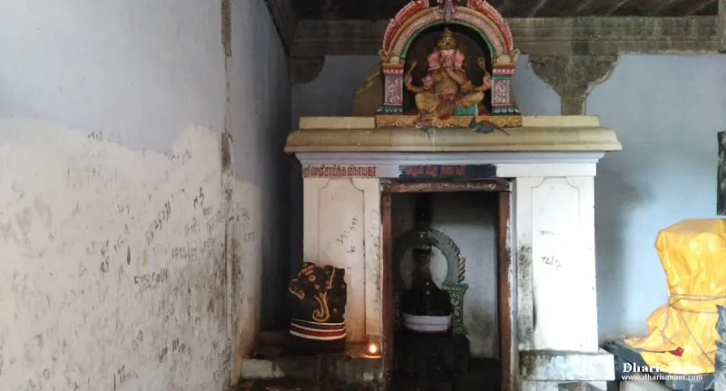 Small whitewashed shrine with a painted Vinayakar figure on its roof and an idol inside