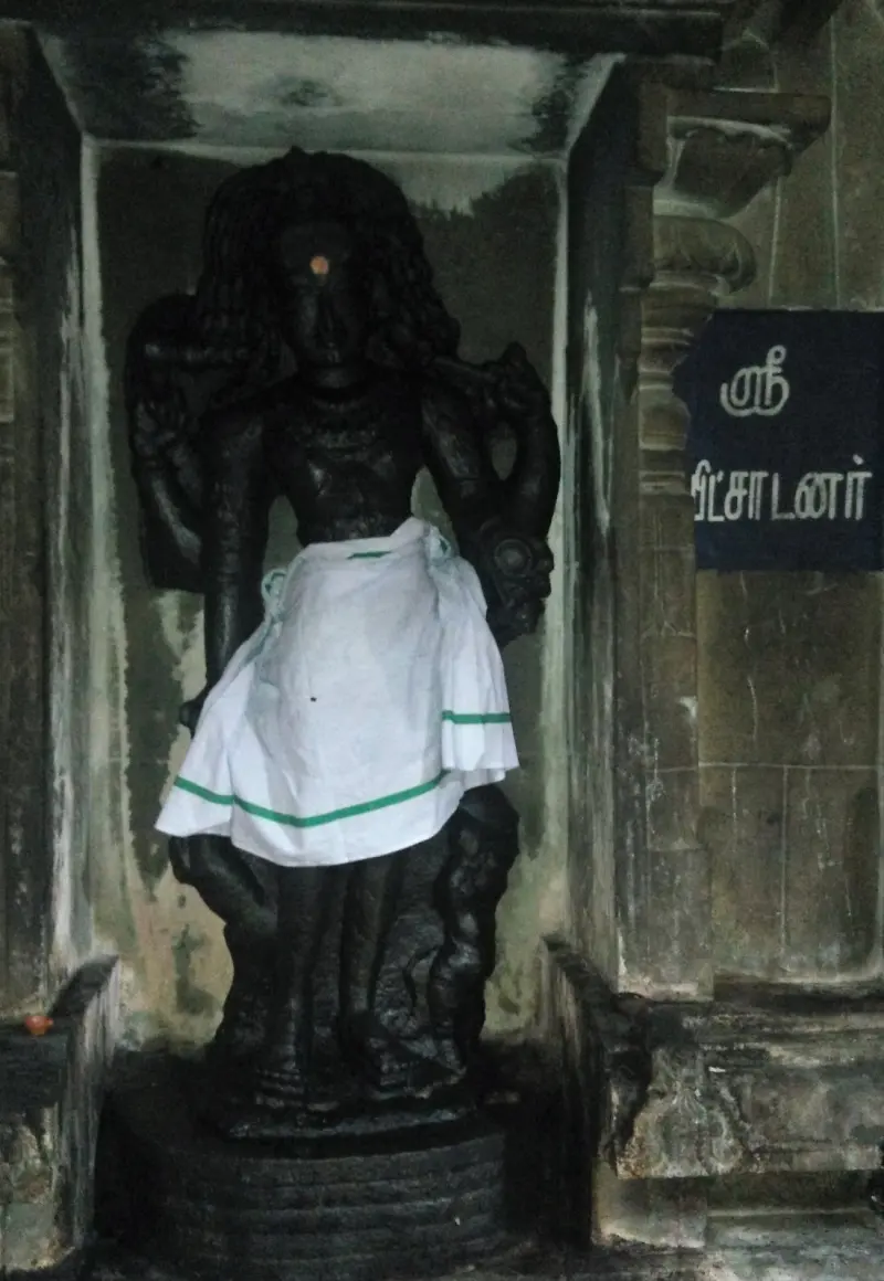 A dark standing figure in a niche wearing a white cloth at the waist