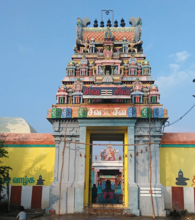 A colorful three-tier tower over yellow walls and gateway