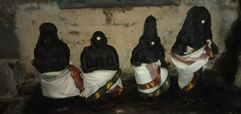 Four black stone idols in a row covered with white cloth
