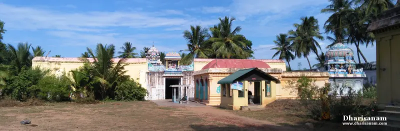 Low yellow temple walls and a small gateway tower among coconut palms, with a covered entrance shed in front