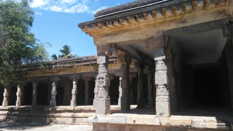 A long stone corridor with carved pillars in the foreground and a shaded passage on the right