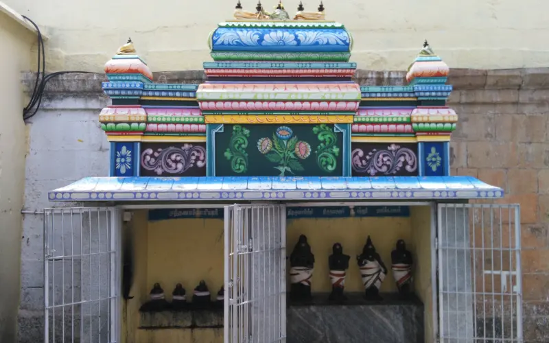 A small painted shrine behind iron gates holding a row of black figures wrapped in cloth