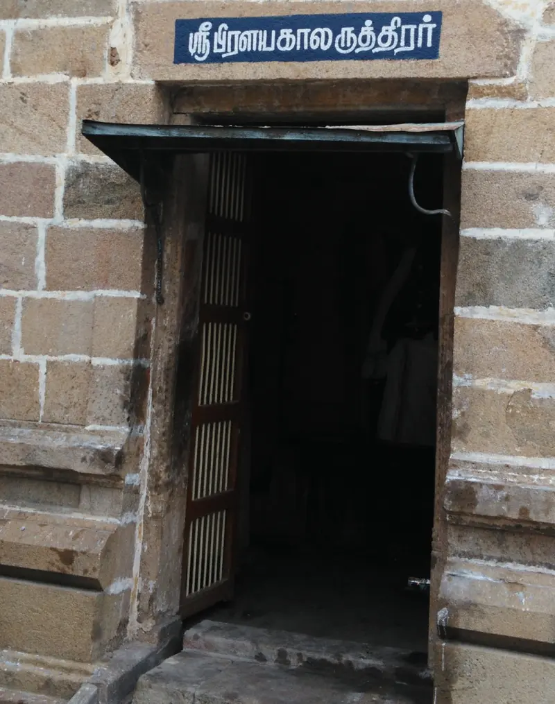 Plain stone doorway with a Tamil name board above it