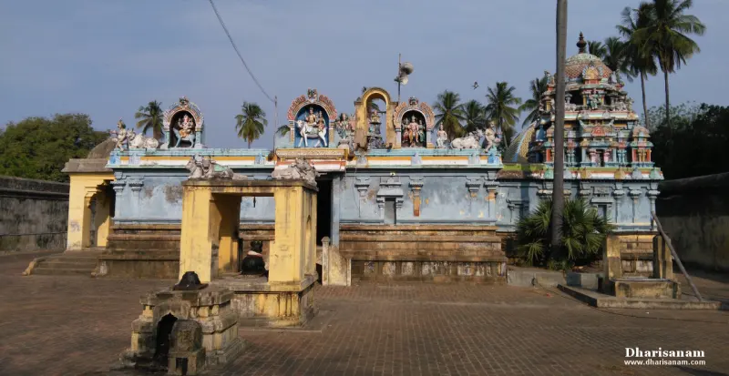 A blue shrine front with a doorway and painted figures above it, a paved courtyard in front