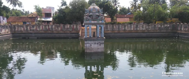 A tank with green water, steps and a small pillared mandapam at its centre