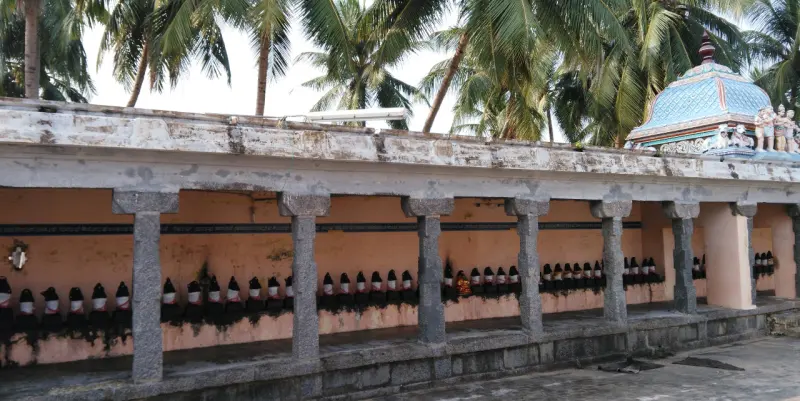 Long pillared corridor with a row of small black idols along the wall