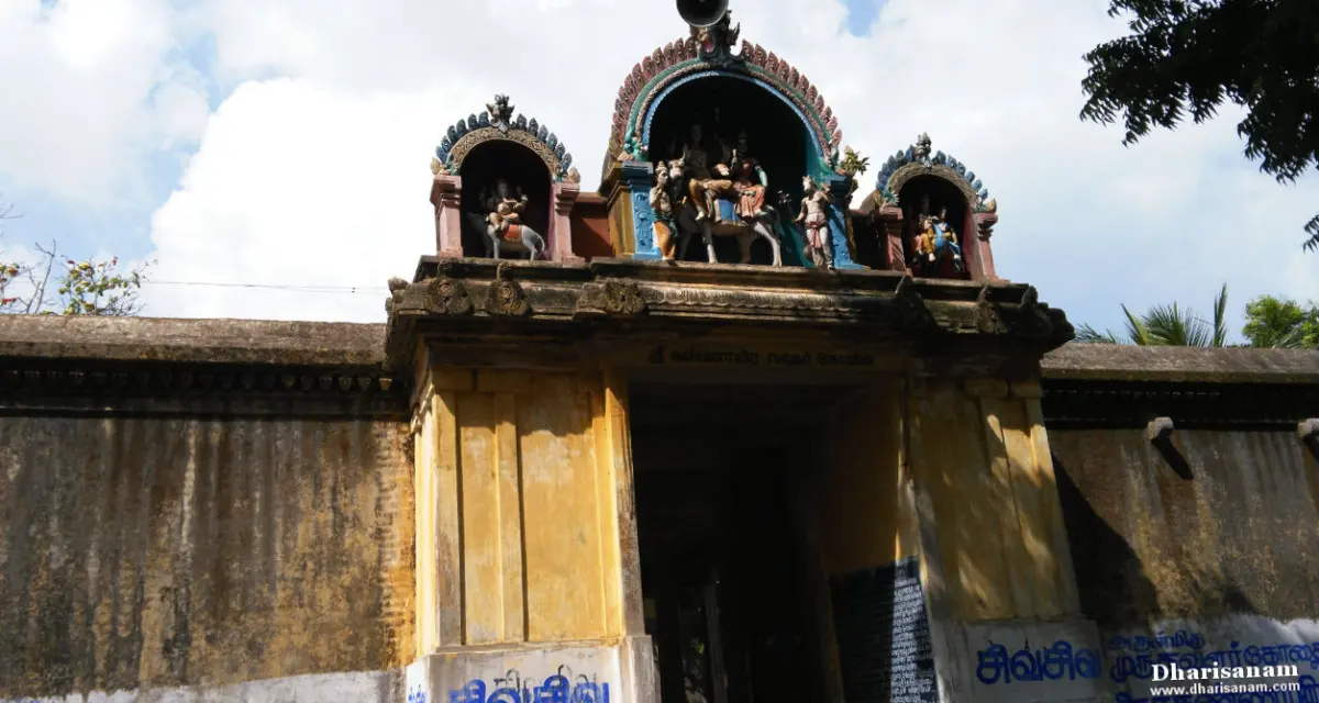 Yellow entrance arch with colourful deity sculptures under a cloudy sky