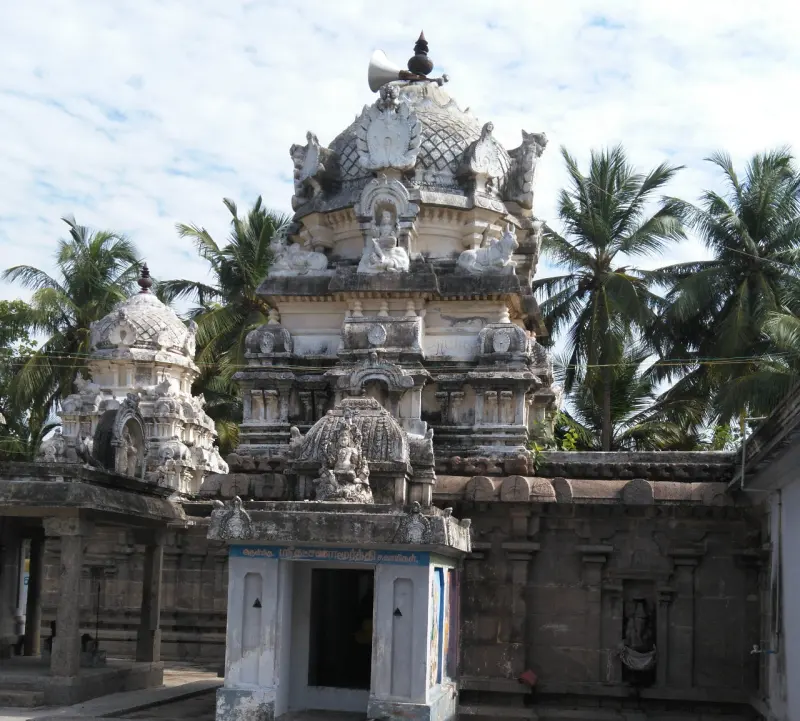 Several stone shrine towers with domed tops and carved figures, framed by coconut palms and a cloudy sky.