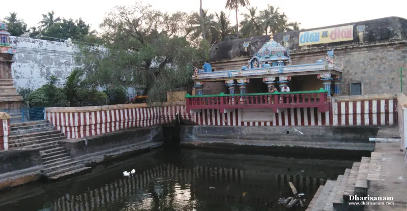 A tank with steps and a red and white striped wall, with a small pavilion and trees beyond