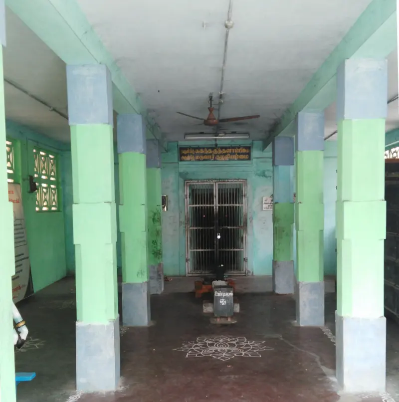 A hall with green and grey pillars facing a barred shrine door, with a flower pattern on the floor.