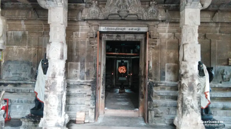 Stone doorway of the sanctum with a Tamil name board above and guardian figures at the sides