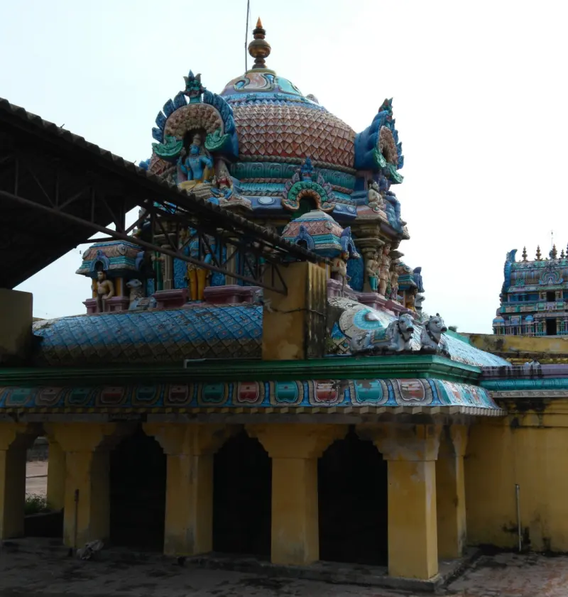 A domed, sculpted tower above a yellow-pillared corridor, with another tower at the right edge.